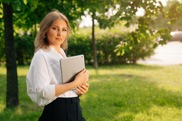 Fototapeta premium Portrait of a confident business girl looking at the camera. Businesswoman holds digital tablet in hand, stern look