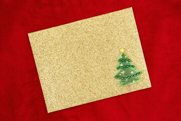 Blank gold glitter greeting card with Christmas tree on red plush fabric mockup