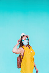 portrait of young woman outdoors over turquoise background wearing protective mask. Summer time and corona virus concept