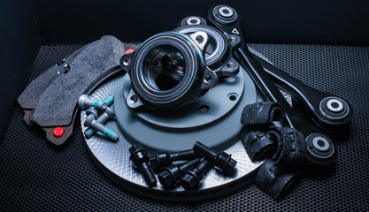 lot of car parts running gear: brake disc, pads and hub bearing with fasteners, isolated on a black background.