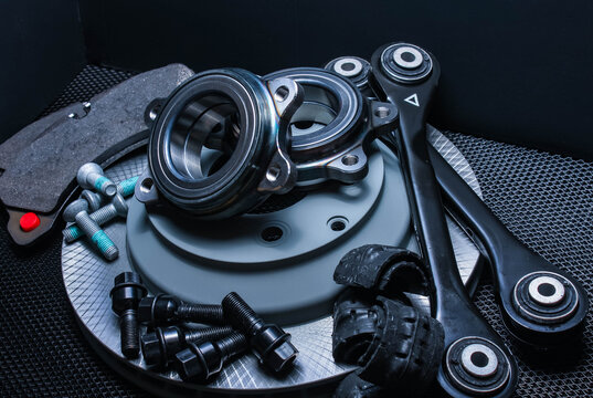 lot of car parts running gear: brake disc, pads and hub bearing with fasteners, isolated on a black background.