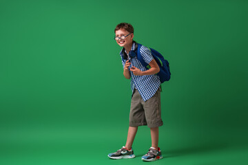 Funny smart Caucasian boy 7 years old with glasses with a school bag.