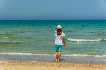 Teenage girl standing on the beach looking backwards