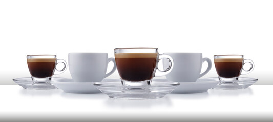 A dynamic row of glass and white expresso cups and saucers full of smooth expresso coffee, on a white style bar or table top with a white backdrop