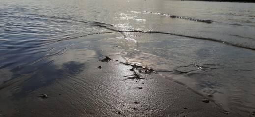 The sun shines beautifully on the sand surrounded on both sides by the sea