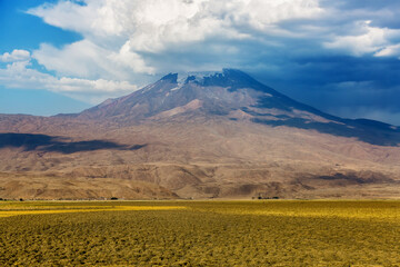 The foot of Mount Ararat. Panoramic view of Mount Ararat from Turkey, Eastern Anatolia. Beautiful landscape with a massif and blue sky. Mountain peak in the clouds