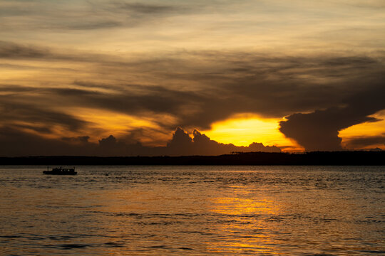 Shocking sun drop with vibrant colors. Golden clouds at sunset. Vacation landscape in the tropics.