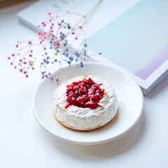 Camembert cheese baked with berry sauce on the background of the magazine. Light daylight