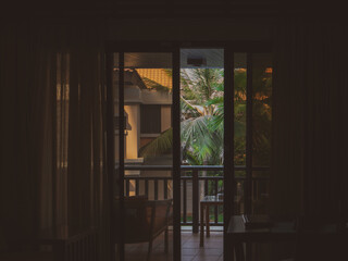 View from a hotel room on the palms outside through a slightly opened balcony glass door.