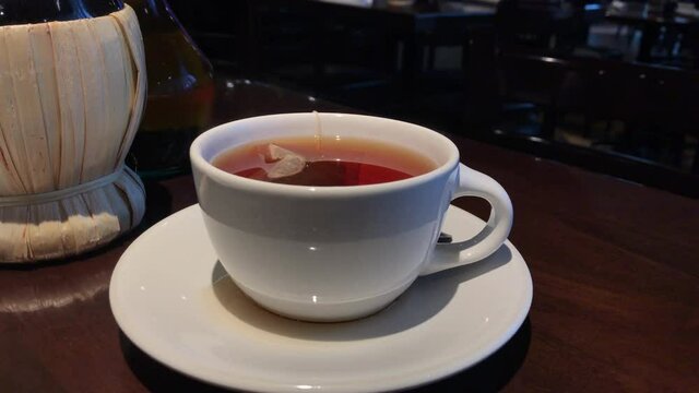 Steamy Cup of Redish Tea Served on a Wooden Table in a Cozy Environment