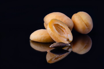 Delicious and ripe apricots with a reflection on a black background.