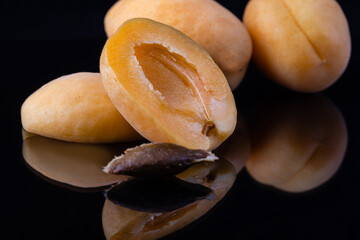 Delicious and ripe apricots with a reflection on a black background.