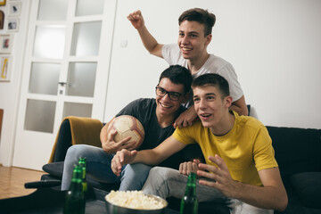 teenager boys having fun at home, watching soccer game on tv