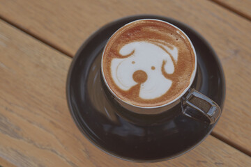 A bear looking latter art on a cup of cappuccino.   