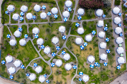 Holiday Bungalows Scattered Around In A Large Green Camping Field, Top Down Aerial View.