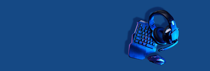 Games keyboard, mouse and headset on blue background.