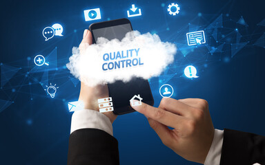 Obraz premium Female hand holding smartphone with QUALITY CONTROL inscription, cloud technology concept