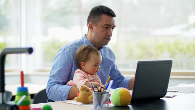 remote job, multi-tasking and family concept - middle-aged father with baby working on laptop at home office