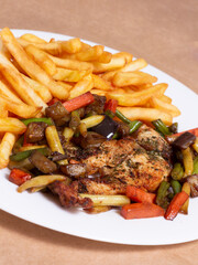 A nice plate of roasted chicken, seasoned with herbs, pepper, salt, oregano, and garlic. Also accompanied by vegetables fried on olive oil.
Accompanied by French fries on a white plate.