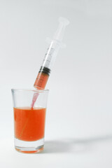 Carrot injection. A glass with carrot liquid and an empty syringe. Syringe on a white background. 