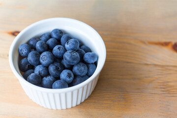 Top view of fresh ripe blueberries in bowl. Juicy and fresh berries on wooden table. Blueberry antioxidant. Concept for healthy eating and nutrition.