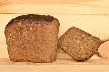 Black cereal bread, macro, on a background of natural wood.