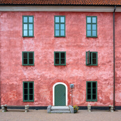 Fototapeta na wymiar An old pink facade with green windows and a green door in full symmetry