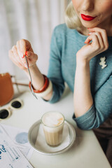 Beautiful blonde model with blue eyes in retro clothes: beret, jacket. Seat in pretty caffe with cup of coffee 