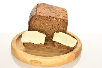 Slices of black cereal bread with butter on a white background.