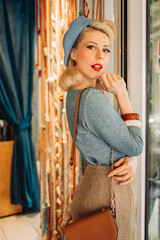 Beautiful girl dressed in retro style in beret with red lips in cafe