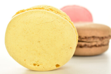 Sweet macaroons, in focus, macro, in the foreground. In the background are two cookies. The background is white.