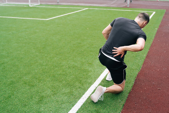 The athlete is holding on to his back. The concept of pain in a sn down during a workout.
