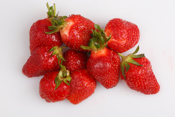 isolated close up top view shot of a bunch of whole and sliced in half vibrant red strawberries on a white background