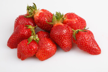 isolated close up top view shot of a bunch of whole and sliced in half vibrant red strawberries on a white background