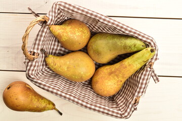 Ripe pears in a basket, close-up, on a white wooden table.