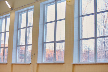 Large Windows in the school gym, covered with netting from ball strikes