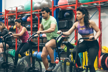 Fototapeta na wymiar Group of athletes doing air bike at the gym