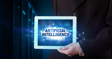 Young business person working on tablet and shows the inscription: ARTIFICIAL INTELLIGENCE