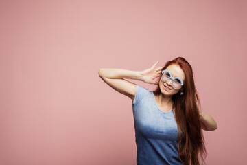 A young woman in sunglasses on a pink background overhears a conversation or news