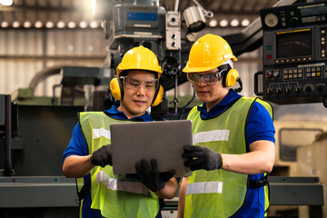 Colleagues in industrial engineering or management of work done Holding a male mechanic. Technicians or engineers are inspecting machine operations using a laptop computer.