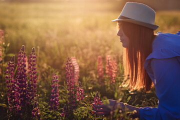 A girl in a field  standing in the rays of the setting sun