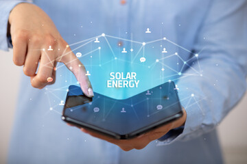 Businessman holding a foldable smartphone with SOLAR ENERGY inscription, new technology concept