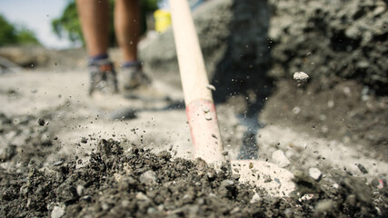 Worker shoveling away gravel dirt
