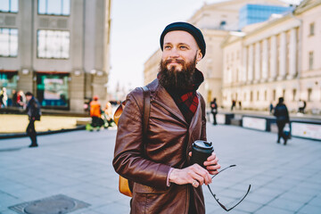 Smiling hipster with cup of coffee and sunglasses in hand