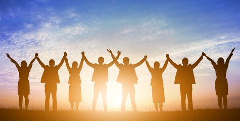 Silhouette of happy business teamwork making high hands over head in sunset sky background for...