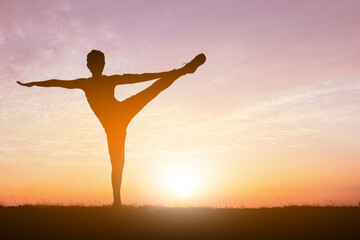 Fototapeta na wymiar Silhouette of gorgeous young woman practicing yoga in sunset sky background.