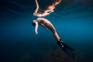 Obraz na płótnie Canvas Woman free diver with fins relaxing underwater in ocean. Woman and reflection