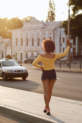 Dark-skinned girl stops a taxi in the city