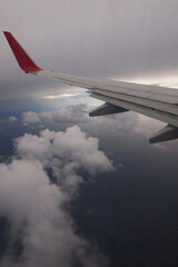 Fototapeta na wymiar Wing of an airplane flying through storm clouds above the ocean
