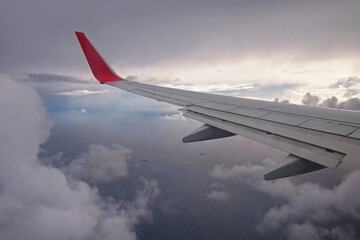 Fototapeta premium Wing of an airplane flying through storm clouds above the ocean